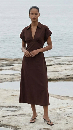 Chocolate Linen Blend Collared Midi Dress modeled by a woman on the beach, showcasing its A-line silhouette and rich chocolate hue.