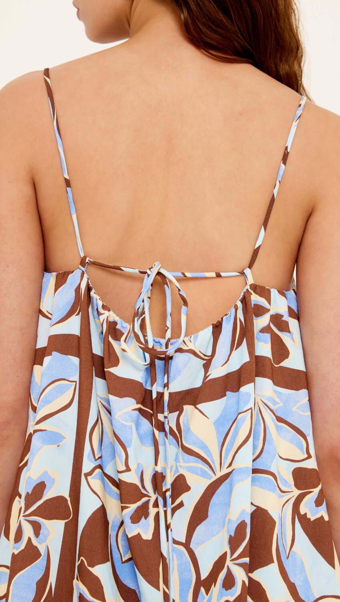 Back view of the Blue Abstract floral Mini Dress showcasing adjustable tie-back straps and flowing silhouette.