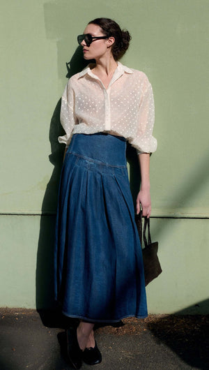 Model wearing a Cream Embroidered Spot Sheer Oversized Shirt with a denim skirt against a green wall.