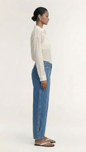 A model wearing a Cream Embroidered Spot Sheer Oversized Shirt paired with high-waisted denim jeans.