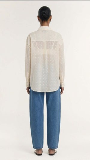 Back view of a model wearing the Cream Embroidered Spot Sheer Oversized Shirt paired with blue jeans.