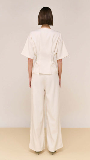 Back view of the Cream Pintuck Button Front Top styled with matching pants, showcasing a sophisticated outfit.