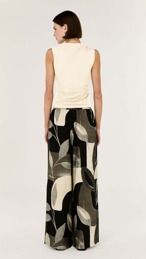 Woman wearing a Cream Ruched Slinky Tank paired with wide-leg patterned pants.