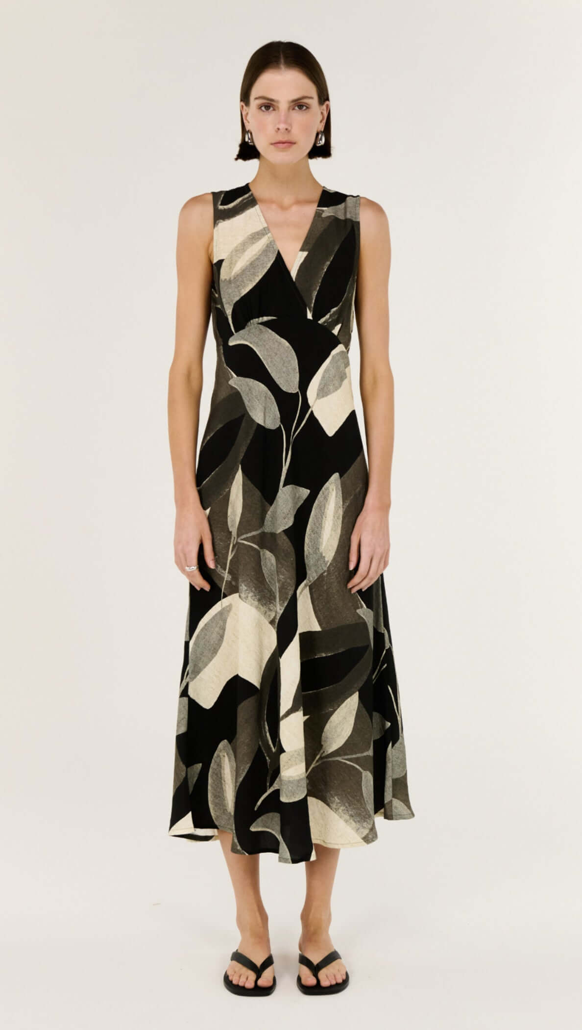 Model wearing the Dark Leaf Bias Midi Dress featuring a V-neckline and fluid silhouette in a leaf print.