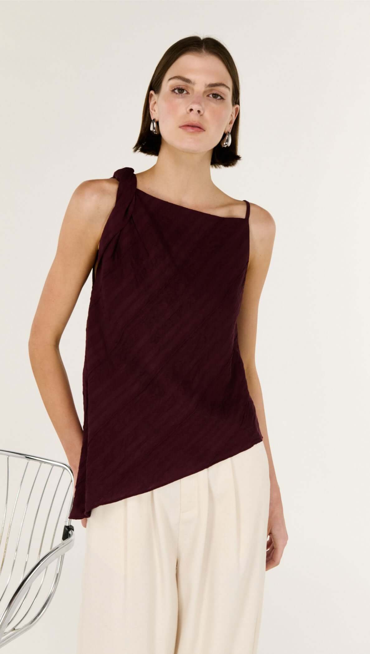 Model wearing Dark Red Textured Asymmetrical Twist Top with asymmetrical neckline and soft drape.