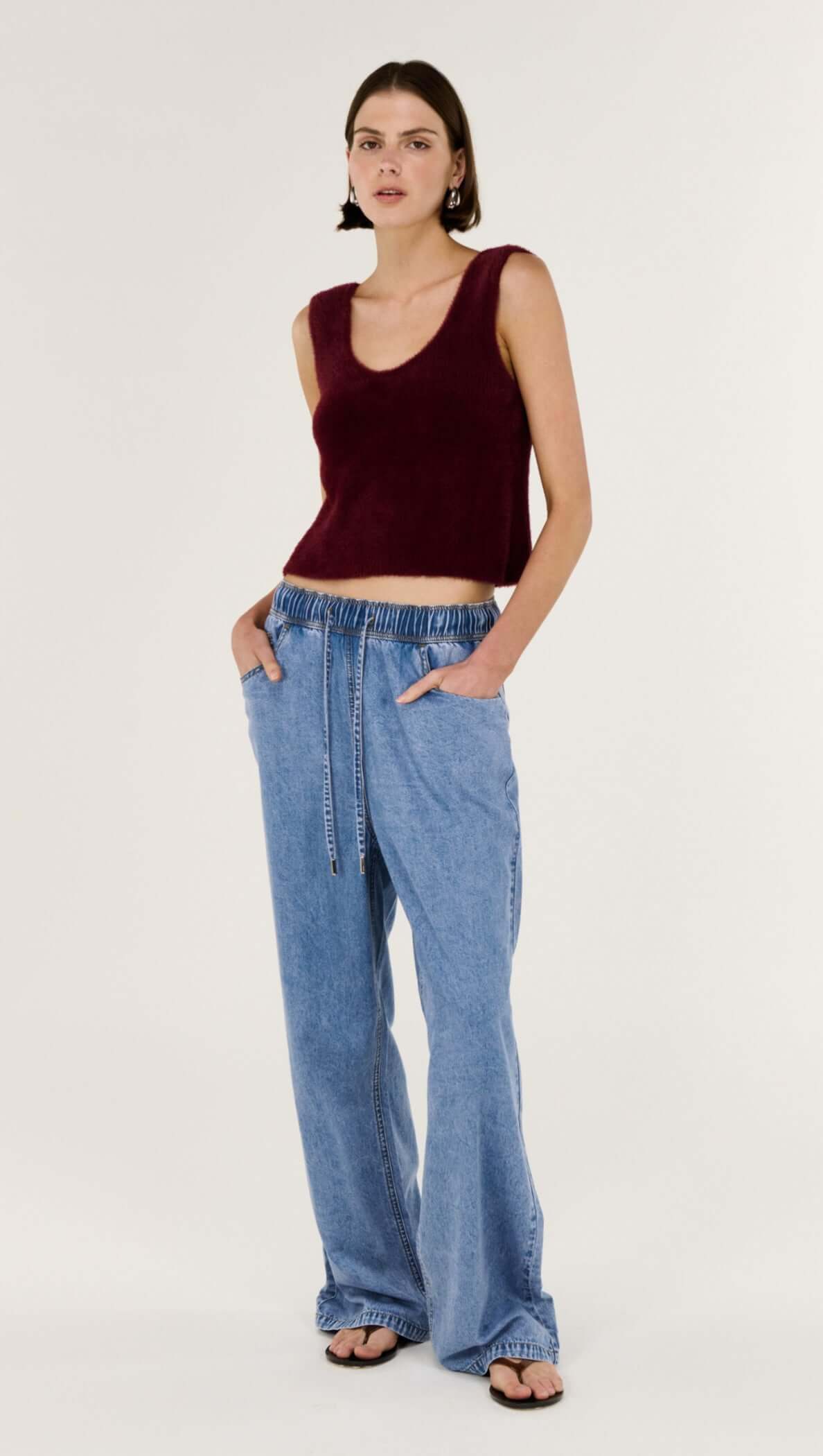 Model wearing a Deep Red Plush Cotton Knit Tank with a scoop neckline, styled with casual denim pants.