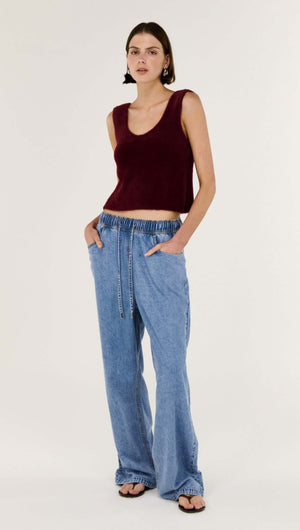 Model wearing a Deep Red Plush Cotton Knit Tank paired with relaxed blue denim pants, showcasing a casual chic style.