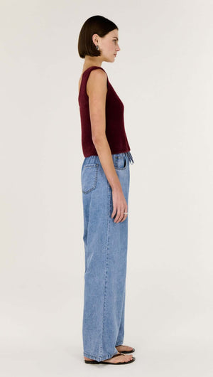 Side view of a model wearing a Deep Red Plush Cotton Knit Tank paired with light blue jeans.