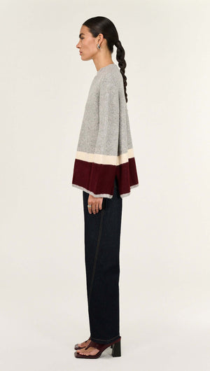 Side view of a model wearing a Grey Raglan Heavy Knit Jumper with color block details and relaxed fit, paired with dark jeans.