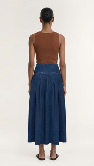 Back view of a model wearing the Indigo Chambray Box Pleat Midi Skirt, showcasing its voluminous, A-line silhouette.