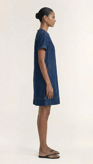 Side view of a model wearing the Indigo Chambray Short Sleeve Mini Dress, showcasing its denim fabric and relaxed fit.