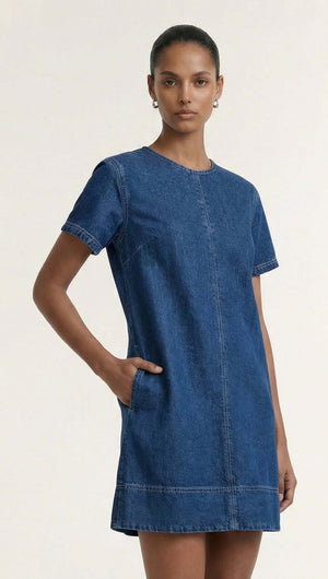 Model wearing the Indigo Chambray Short Sleeve Mini Dress, showcasing its sleek design and denim fabric.