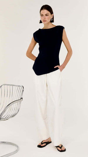 Navy Boat Neck Knit Top worn with white trousers in a modern, stylish setting.