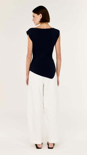 Navy Boat Neck Knit Top featuring a sculpted silhouette and asymmetrical hem, worn with wide-leg trousers.