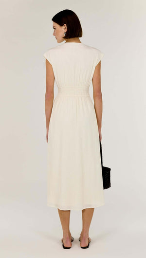 Back view of a model wearing the Cream Cotton V-Neck Midi Dress featuring soft cap sleeves and defined waist.
