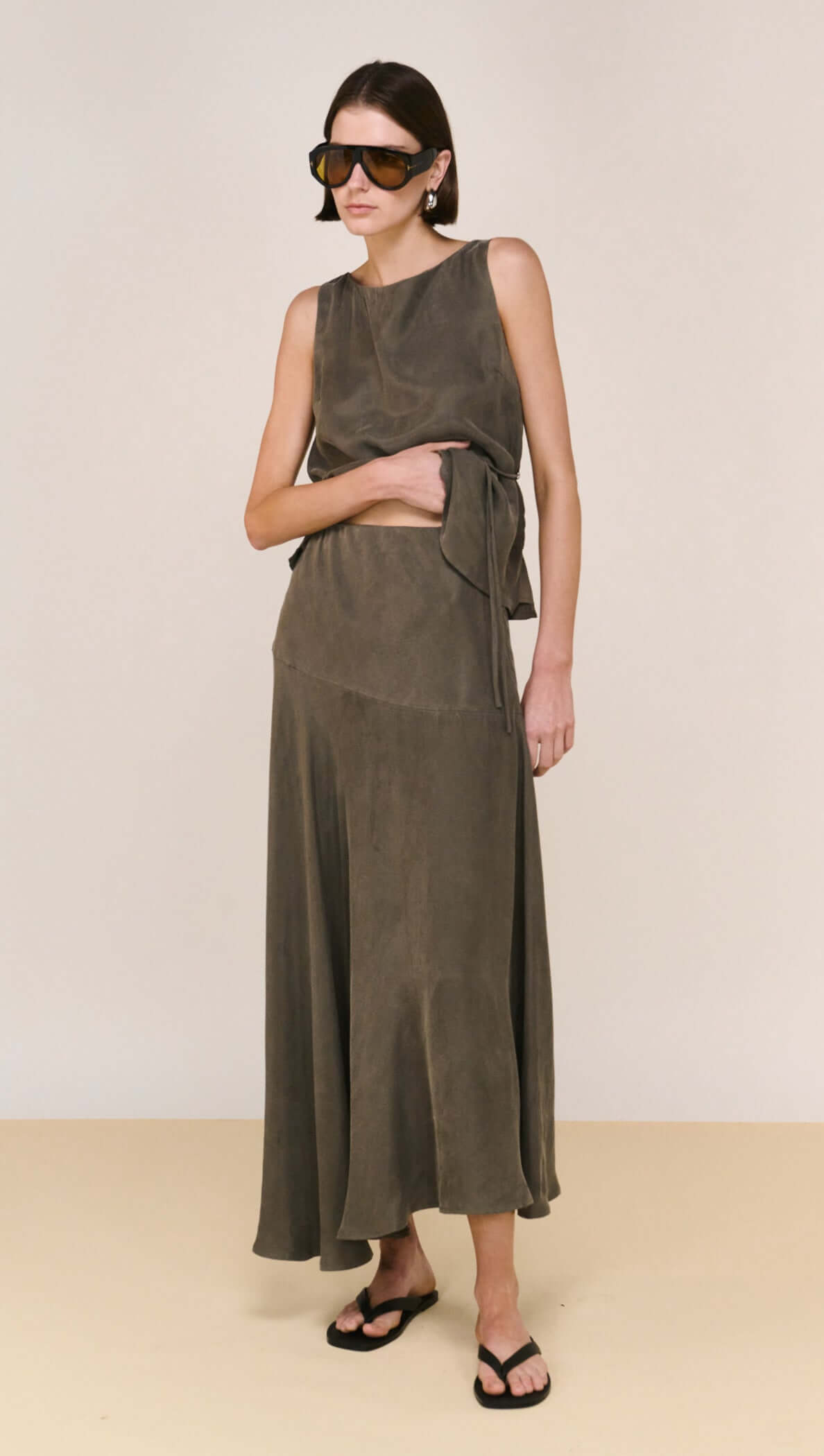 Model wearing the Olive Cupro Asymmetrical Hem Maxi Skirt, showcasing its luxurious movement and elegant silhouette.