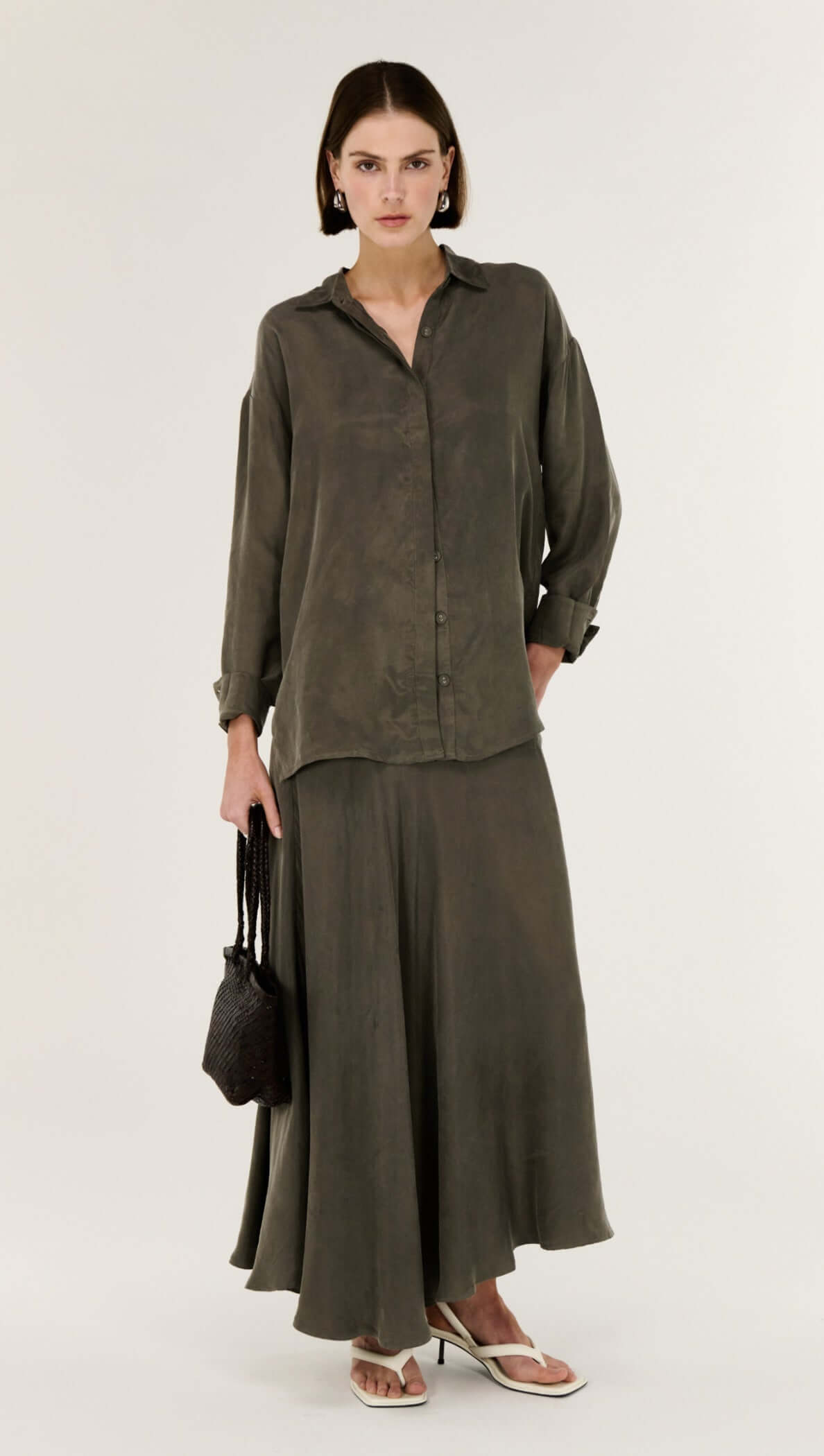 Model wearing an Olive Cupro Oversized Shirt paired with a matching skirt, showcasing modern style and fluid silhouette.