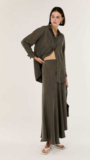 Model wearing the Olive Cupro Oversized Shirt with matching skirt, showcasing a modern and fluid silhouette.