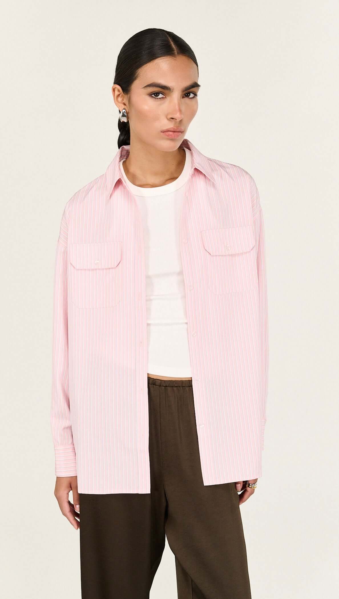 Model wearing a relaxed-fit Pink Pinstriped Shirt with classic collar and vertical stripes for a chic casual look.