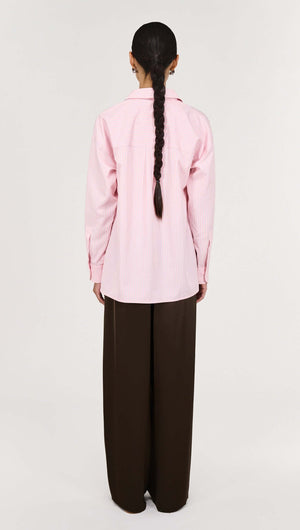 Woman wearing a Pink Pinstriped Shirt with a relaxed silhouette and detailed back view.