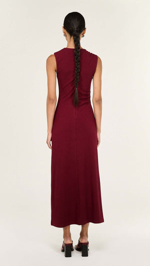 Back view of a model wearing the Red Stretch Jersey Midi Dress with a sleek silhouette and draped detailing.