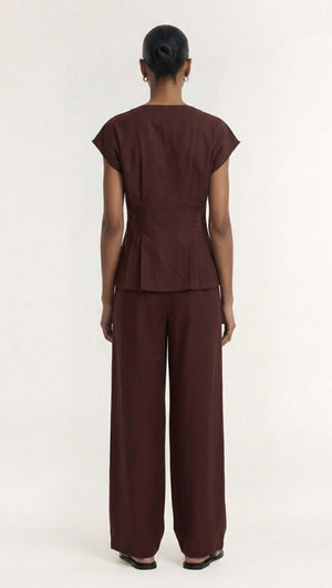 Model wearing the Rhodes Chocolate Linen Blend V-Neck Cropped Top, showing the back view, styled with wide-leg pants.