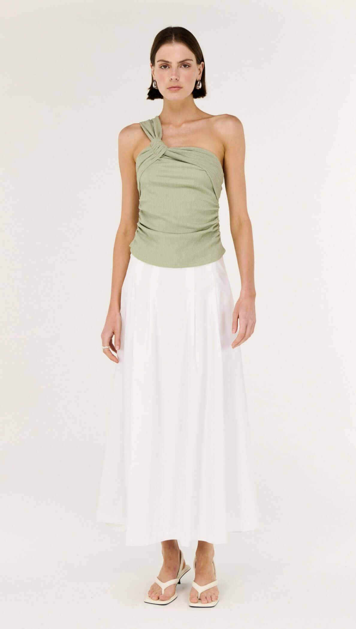Sage One Shoulder Knotted Top worn by a model, featuring a twisted neckline and body-skimming fit in sage green.