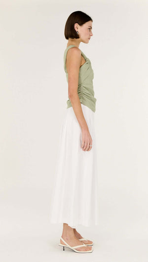 Model showcasing the Sage One Shoulder Knotted Top paired with a flowy white skirt.