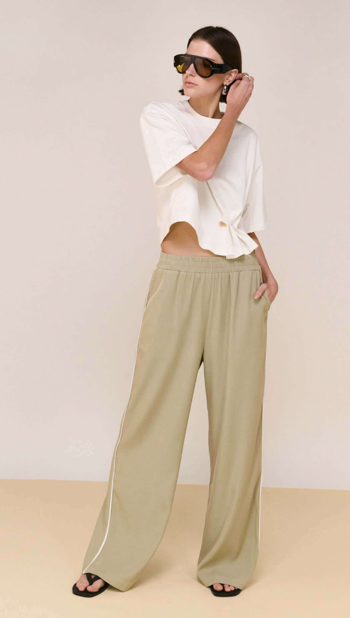 Woman wearing Sage Relaxed Track Pant with elasticated waistband and side stripe for casual style.