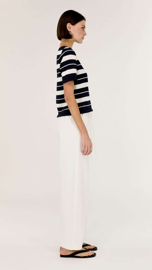 Striped Crew Neck Knit Tee worn with white pants, showcasing a side profile of the model.