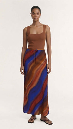 Model wearing the Sunset Ombre Print Bias Maxi Skirt in an abstract cobalt and rust pattern.