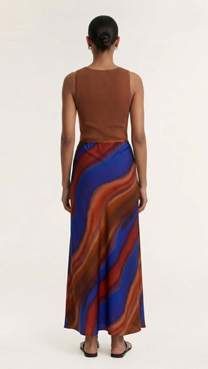 Model showcasing the back view of the Sunset Ombre Print Bias Maxi Skirt with an abstract cobalt and rust design.