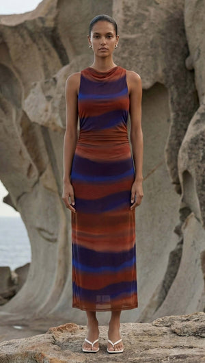 Sunset Ombre Print Sleeveless Mesh Midi Dress modeled outdoors against a rock backdrop, showcasing its unique design.