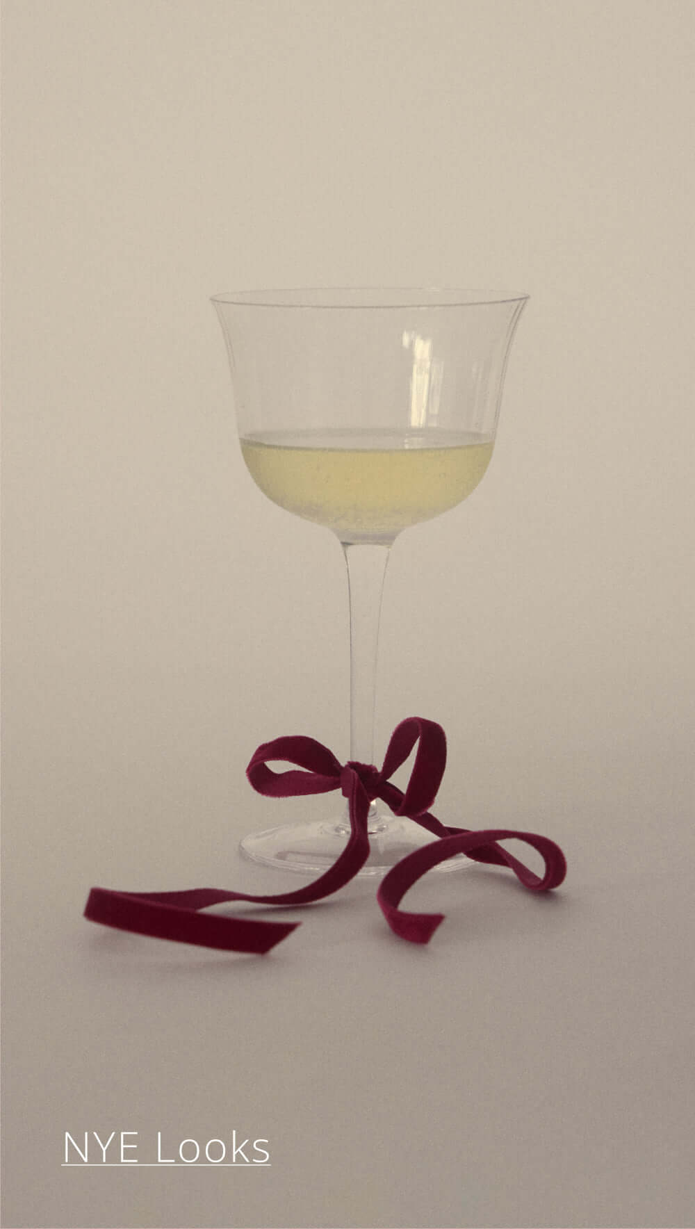 Elegant glass of champagne with burgundy ribbon, perfect for NYE celebrations.
