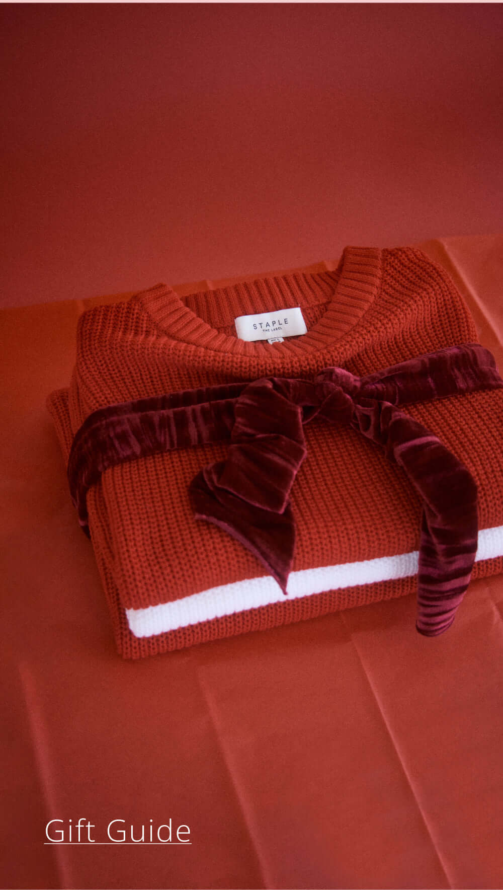 Cozy red sweater wrapped with a velvet bow, perfect for holiday gift guides.