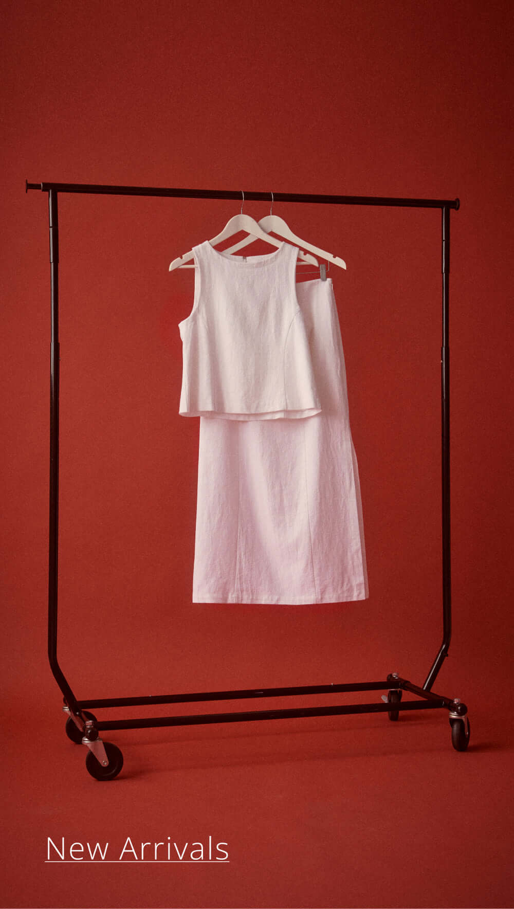 New arrivals featuring a stylish white top and dress on a clothing rack against a red background.