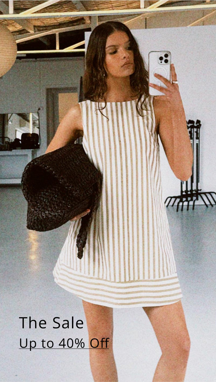 Woman in a striped dress holding a black bag, with a sale banner at the bottom.