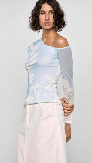 Model showcasing the Aurora Mesh Top, featuring blue and ivory floral mesh, one-shoulder neckline, and sheer long sleeves.