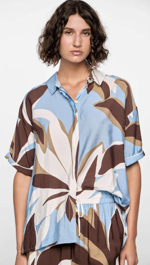 Model wearing a Maeve Resort Shirt with bold abstract print in brown, blue, and cream, featuring a relaxed fit and collared neckline.