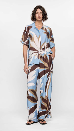 Model wearing the Maeve Resort Shirt with a bold abstract print in brown, blue, and cream, styled casually for summer.