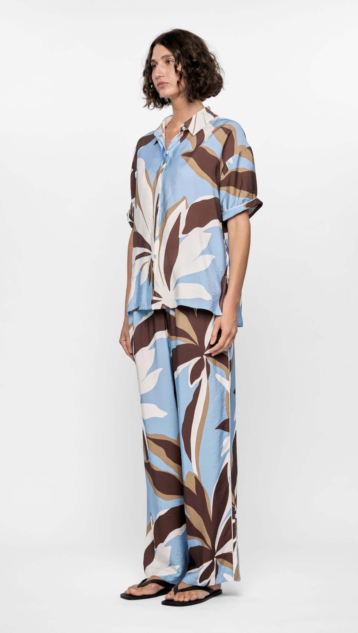 Model wearing the Maeve Resort Shirt with abstract floral print in blue, brown, and cream, styled with matching relaxed pants.