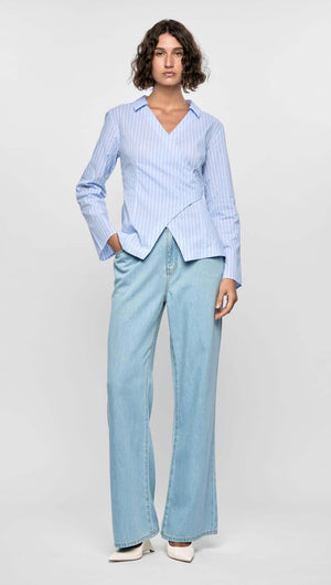Model wearing the Ayra Pinstripe Wrap Top with light blue stripes, paired with wide-leg denim jeans.