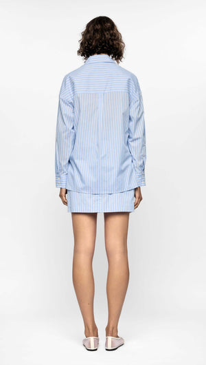 Back view of a model wearing a blue striped Ayra shirt with relaxed fit and modern hem.