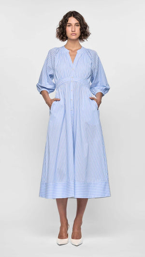 Woman wearing the Myra Midi Dress featuring soft blue pinstripes, puff sleeves, and a flattering empire waist.