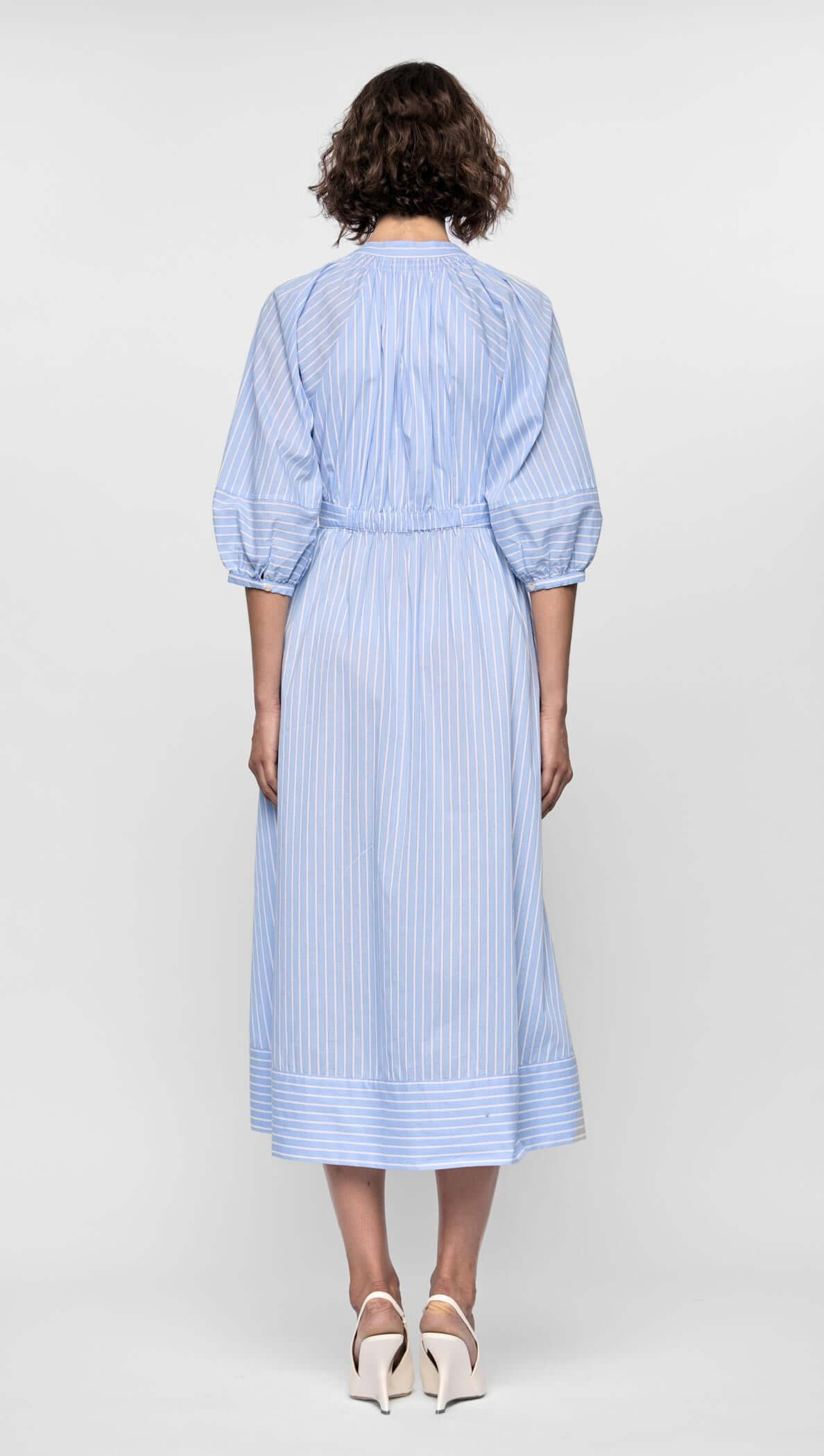 Back view of the Myra Midi Dress in soft blue stripes, featuring puff sleeves and a full skirt.