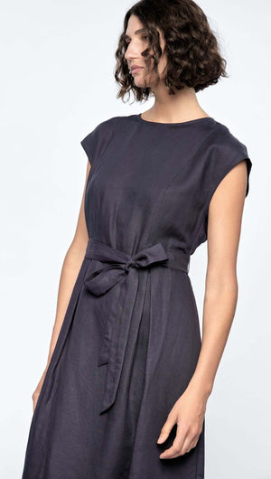 Model in a sleeveless Rhea Midi Dress, featuring a self-tie belt, deep navy color, and cap sleeves.