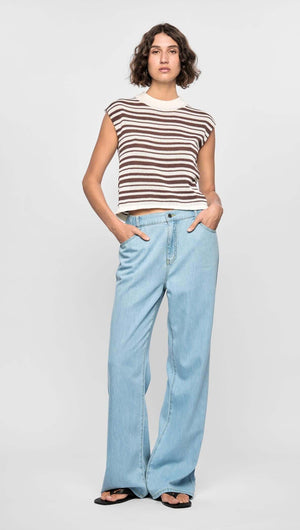 Model wearing the Palmer Stripe Knit Tank with cream and chocolate stripes, paired with light blue denim pants.