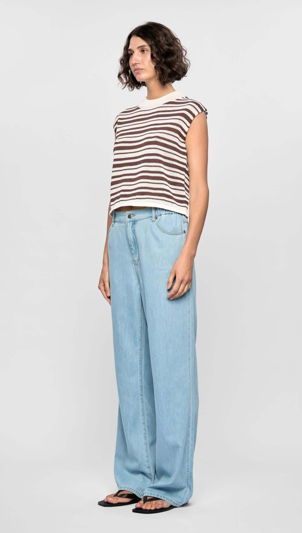 Model wearing Palmer Stripe Knit Tank with cream and chocolate stripes, relaxed fit, paired with light blue wide-leg jeans.