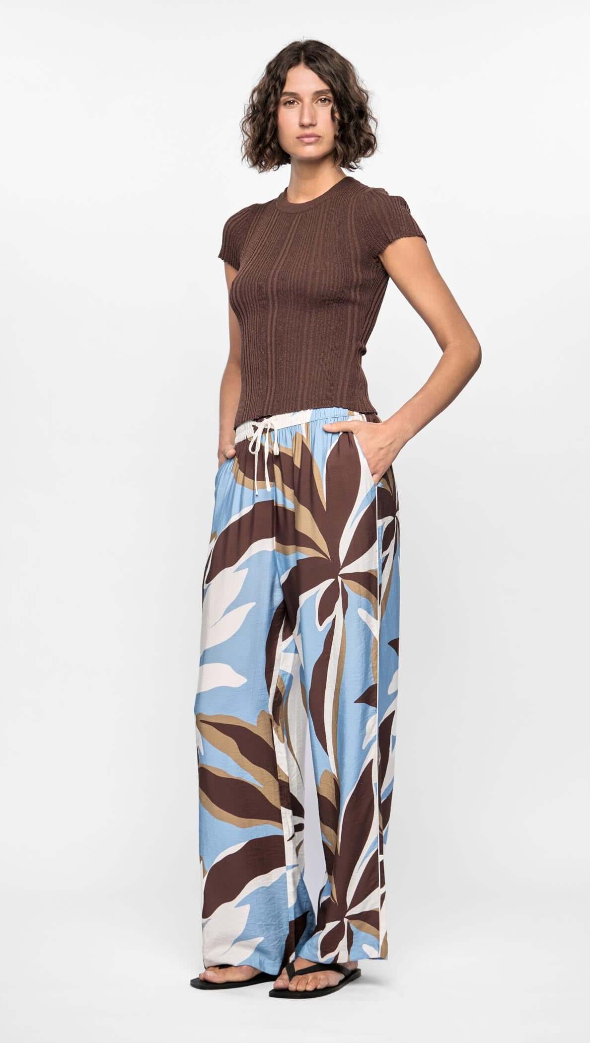 Model wearing Maeve Relaxed Pants featuring abstract brown, blue, and cream print with a wide-leg silhouette and elasticated waistband.