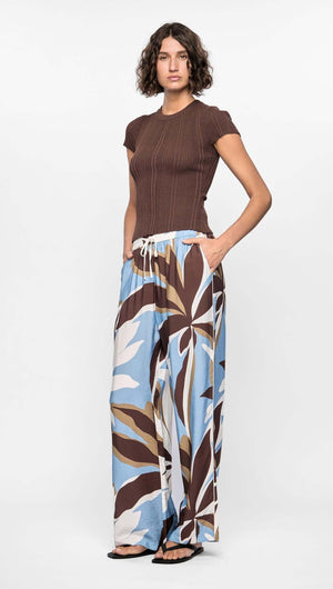 Model wearing Maeve Relaxed Pants featuring abstract brown, blue, and cream print with a wide-leg silhouette and elasticated waistband.